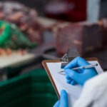 Technicians maintaining records on clipboard at meat factory